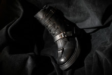 Black Leather Boot With Buckles And Laces On A Dark Background.