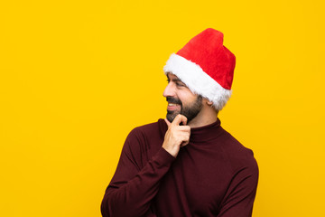 Man with christmas hat over isolated yellow background looking to the side