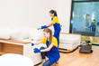 © xartproduction - professional cleaning service. Two women in working uniform, in aprons. Two women in working uniform, in aprons, divide the cleaning of private house, cottage. Washing , vacuum cleaning the sofa