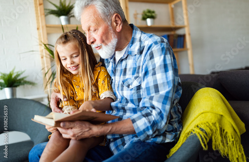 Fotomural Bearded grandfather and his grandchild are having fun reading a book together