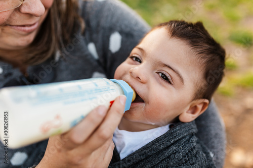 Nino Bebe De Un Ano Tomando Leche De Biberon En Las Manos De La Madre Mientras Se Rie Conteto Y Sonriente Stock Photo Adobe Stock