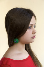 Closeup Portrait Of A Girl With Long Blonde Hair And An Earring In Her Ear In The Shape Of A Green Ball. Christmas Cozy Fun Preparing Concept. New Year Positivity Festive Concept. St.Patrick 's Day