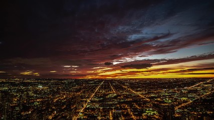 Wall Mural - city aerial view night timelapse looking towards the horizon as the sunset produces pink orange, yel