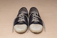 Old Dirty Shabby Sneakers Over Light Wooden Background