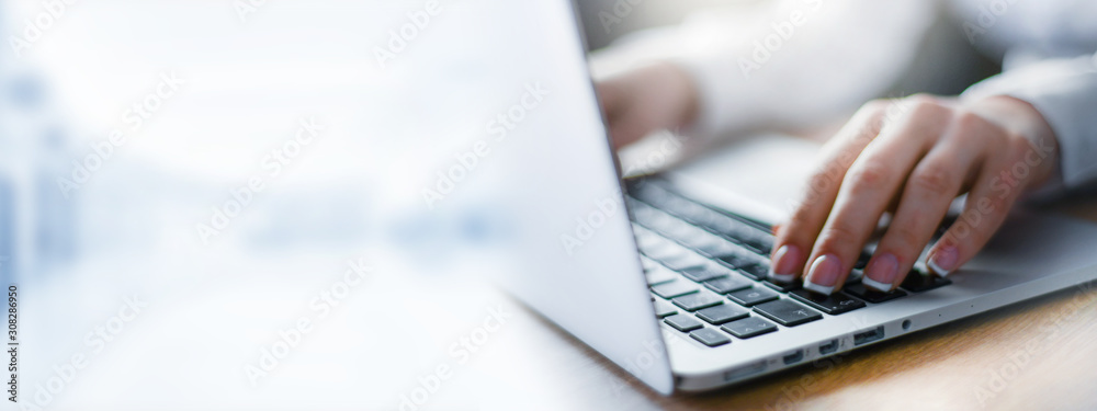 Business woman working on modern computer banner or panorama. Person buying online at internet. Laptop focused on keyboard detail with blur hand. copy space for text. - obrazy, fototapety, plakaty 