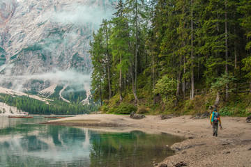 Wall Mural - young tourist hiker man walking at beautiful alpine lake lago di braies (pragser wildsee) in trentin