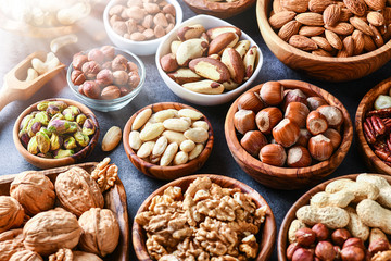 Wall Mural - Mixed nuts in wooden bowls on black stone table. Almonds, pistachio, walnuts, cashew, hazelnut. Top view nut photo.