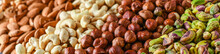 Mix Nuts On Dark Stone Table In Line Top View. Nut Background, Copy Space For Text Concept.