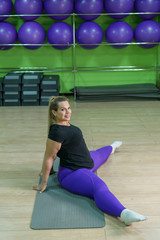 Wall Mural - A fat woman is engaged in fitness in the gym. A girl with a lot of overweight trying to lose weight with the help of sports, does stretching exercises.