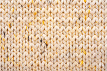 Texture Of Wool Knit Beige Fabric Interspersed With Yellow Yarn. Sweater Background Close-Up View