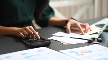 Closeup female calculate saving money on home table.