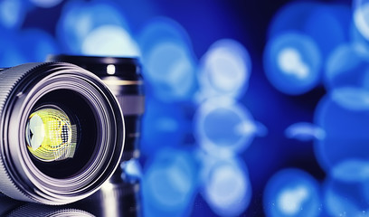 Equipment videographer and photographer. Lenses on the table against the background of bright lamps. Glare and bokeh in reflection of camera glass.