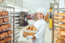 A Baker Woman Holding A Basket Of Baked In Her Hands At The Bakery