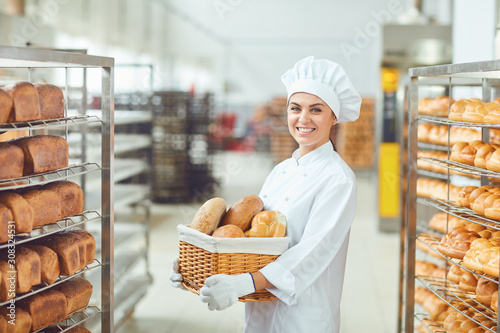 Cuadros en Lienzo A baker woman holding a basket of baked in her hands at the bakery
