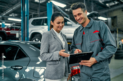 Fotomural Beautiful businesswoman and auto service mechanic are discussing the work and signing documents