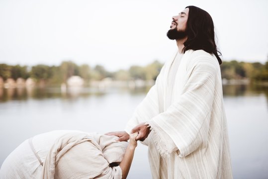 Shallow focus shot of Jesus Christ healing a female with his hand on her head