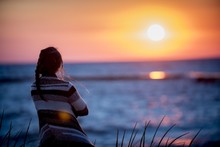 Shallow Focus Shot From Behind Of A Female Looking At The Sea At Sunset
