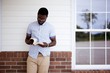 Male leaning against a wall while reading the bible
