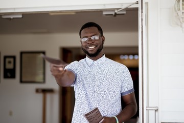 Wall Mural - Shallow focus shot of a male holding a pamphlet towards the camera while smiling