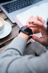 Close up woman using smartwatch working on laptop