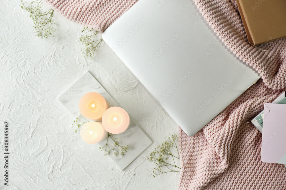 Burning candles, flowers and laptop on table