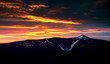 Dramatic sunset sky with illuminated clouds in the mountains. Dark black silhouette of mountain ridge and Jested transmitter tower at the bottom, dark, winter, nihgt.