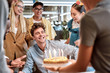 © Svitlana - Wish you all the best. Young cheerful man is going to blow candles on cake and make a wish while celebrating birthday with colleagues