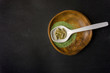 Top view of Kratom powder in wooden bowl and spoon and Kratom capsules