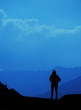© raisondtre - Young tourist woman standing on top of mountain and looking at a beautiful landscape. girl tourist relax on hill in summer epic sky up view. High peak tour Classic blue pantone color year 2020 concept