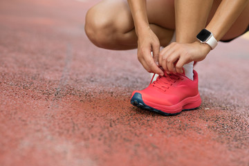 Wall Mural - female runner tying shoelace before running on park trail