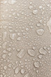 Texture of water drops on fabric textile close-up. Rain background in beige color. Waterproof surface abstract. 