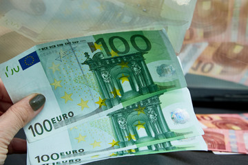 Euro banknotes in the woman hand near dashboard and their reflection in the windshield inside of a car