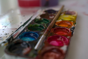 set of used watercolor paints with brush closeup. children's creativity