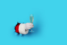 Santa Holding Champagne Flute Isolated Over Light Blue. Hand And Arm Only