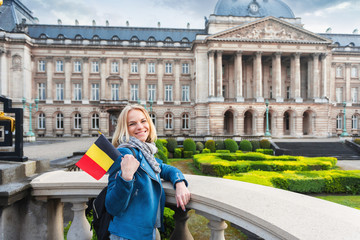 Wall Mural - Woman with the flag of Belgium stands against the backdrop of the Royal Palace in Brussels, Belgium