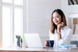 © NAMPIX - Portrait of young businesswoman smiling and looking at camera while sitting at office desk in modern office.
