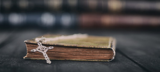 Holy Bible, Christian cross necklace on a wooden background.