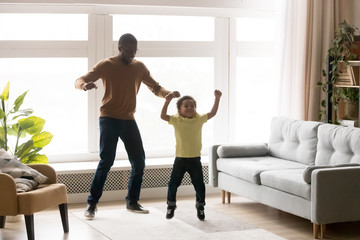 Wall Mural - Happy black dad and son have fun jumping together