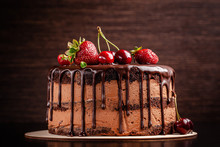 Chocolate Cake With With Berries, Strawberries And Cherries. Cake On A Dark Brown Background. Copy Space