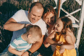 Wall Mural - Portrait of a beautiful big family having fun outdoor in a field of flowers while mother and father is tickling their children.