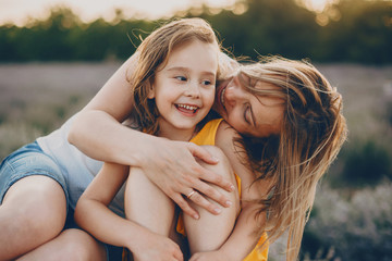 Wall Mural - portrait of a charming young woman embracing her little daughter and kissing her on the cheek while 