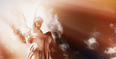 Wall Mural - antique statue of wonderful angel in the rays of the sun on sky background. horizontal image. (archi