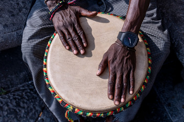 Close up of hands of a black man playing a drum