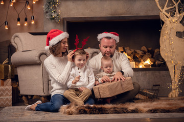 Picture of happy parents with son at fireplace, deer with garland in room