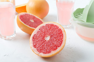 Fresh and tasty grapefruits, glasses of juice, manual juicer on the white table