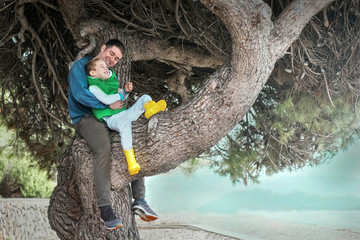 Happy childhood, father and son sit on a tree on a sunny day, fa