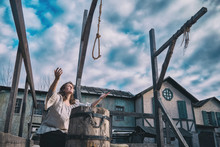 Woman Raises Her Hands To The Sky At The Place Of Execution, The Area With The Gallows At The Scaffold