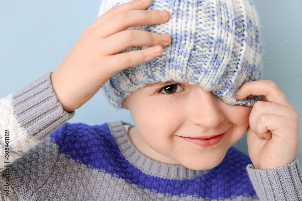 Cute boy in winter clothes on color background