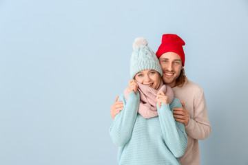 Wall Mural - Happy couple in winter clothes on color background