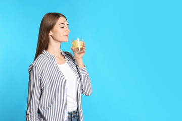 Sticker - Young woman with glass of lemon water on light blue background. Space for text